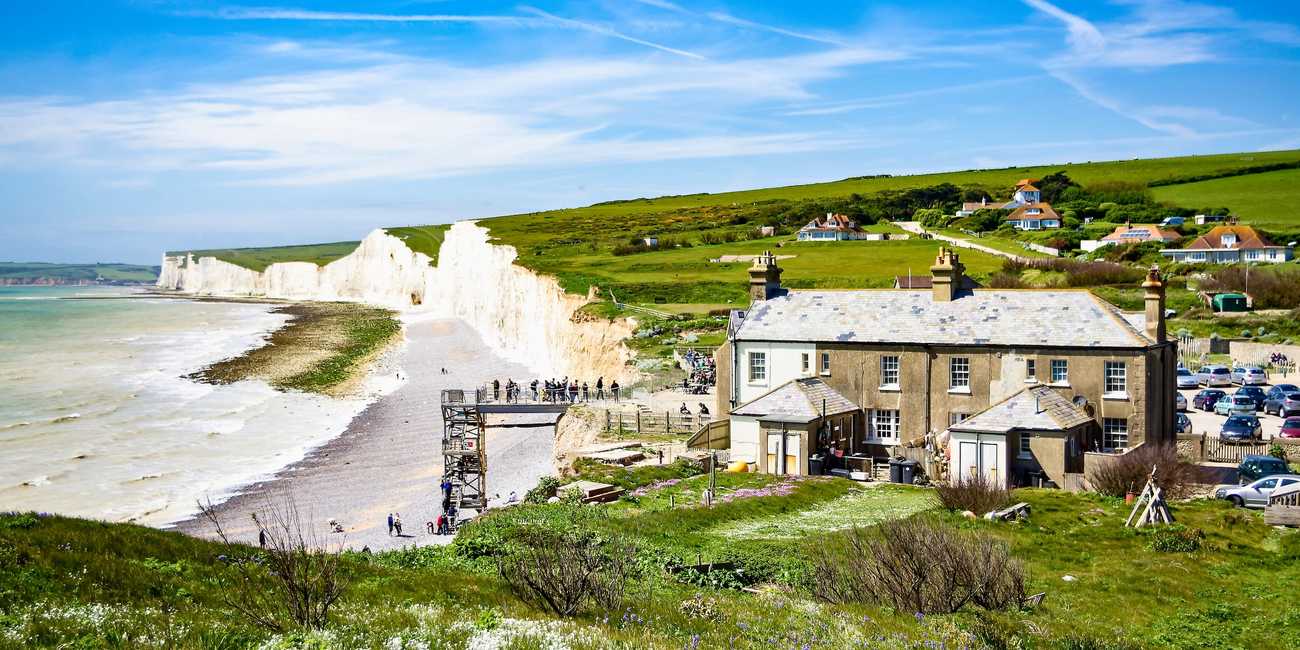 Birling Gap and the majestic Seven Sisters Cliffs coastal trail in 2026 Scenic view of the historic Birling Gap building and beach access platform with the white chalk Seven Sisters Cliffs stretching into the background